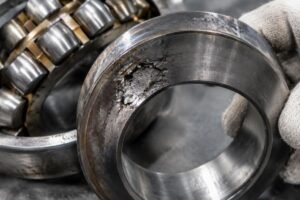 Close-up inspection of a damaged spherical roller bearing inner ring showing fatigue spalling